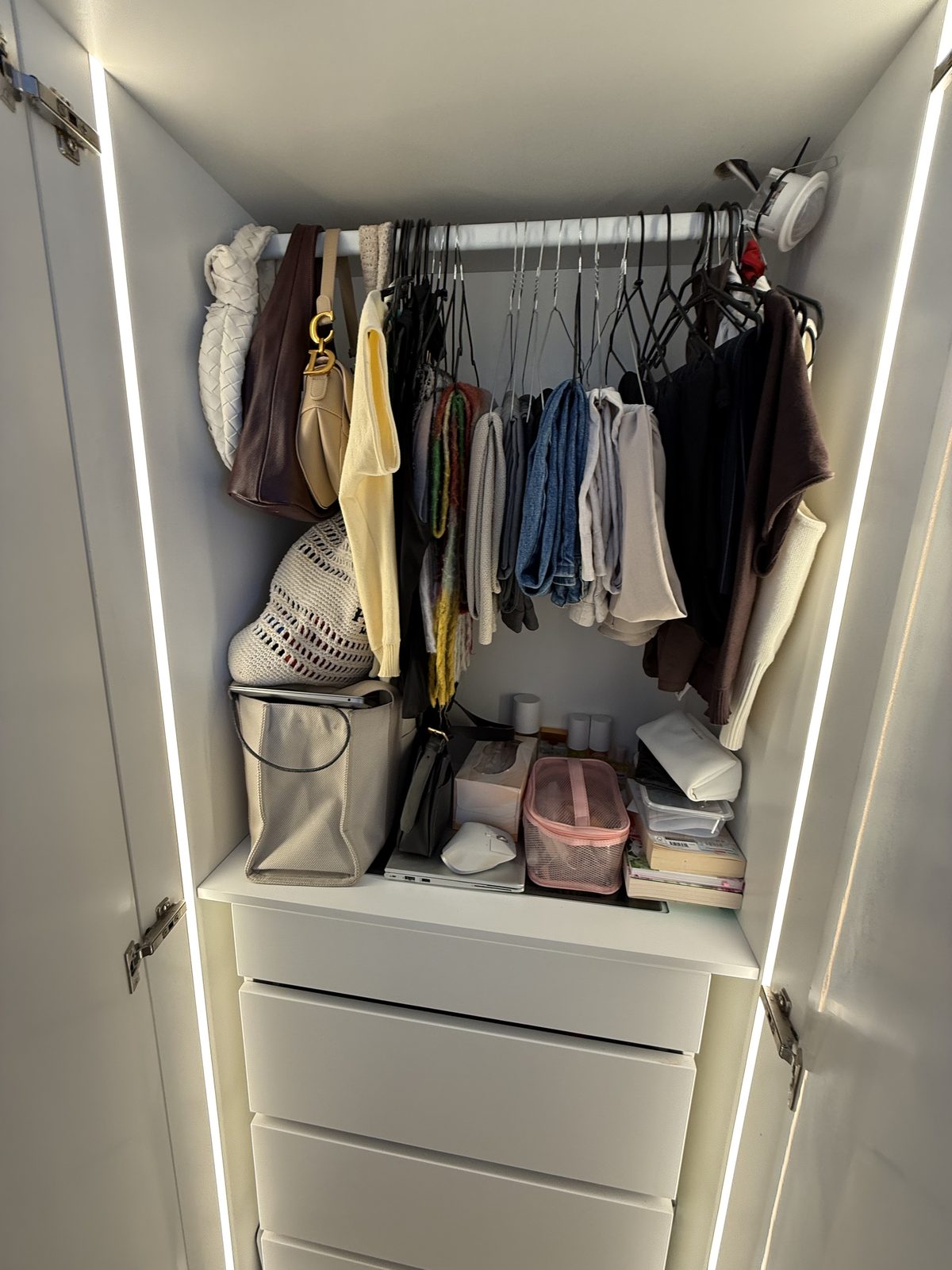 Walk-in wardrobe with vertical LED strip lighting along the shelving columns and ceiling perimeter